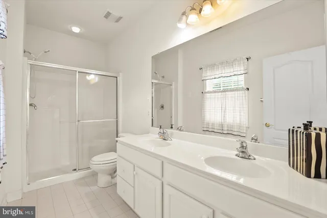 a bathroom with a double vanity sink toilet and shower