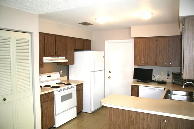 a kitchen with a refrigerator a stove top oven a counter space and wooden floor