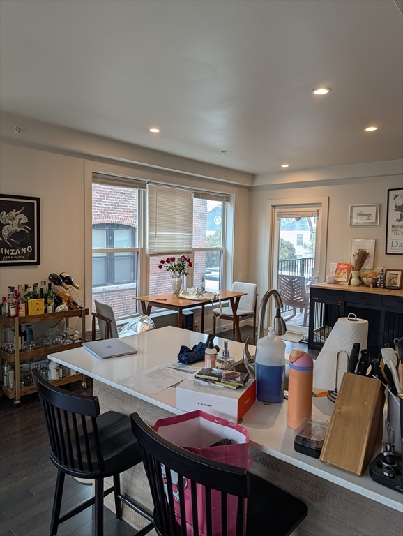 3383 Washington Street, Unit 201 Boston, MA 02130 - Photo 4 of 15 a view of a dining room and livingroom with furniture wooden floor a rug a painting and a chandelier