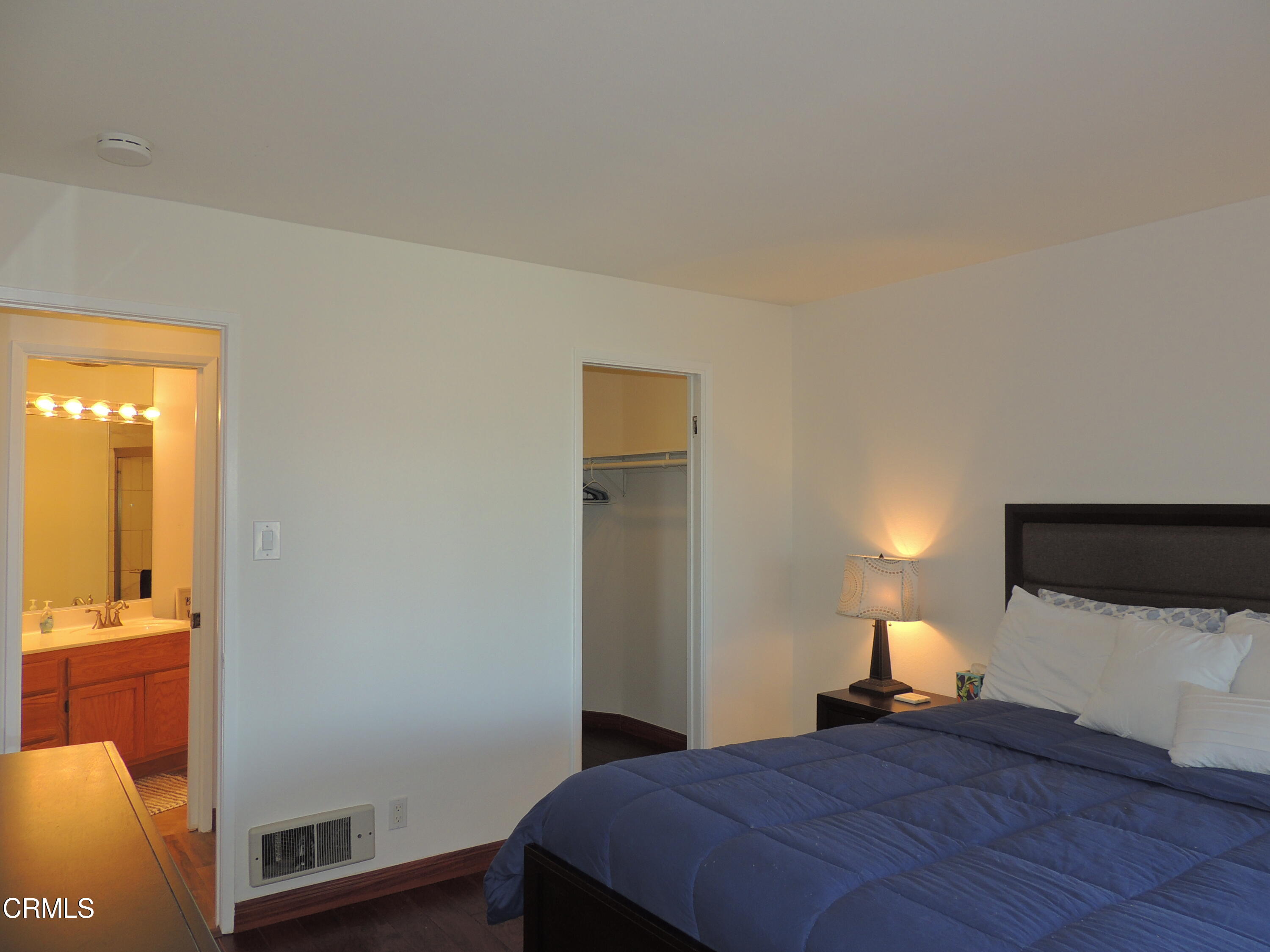 2901 Peninsula Road, Unit 237 Oxnard, CA 93035 - Photo 9 of 35 a bedroom with a bed and a lamp with wooden floor