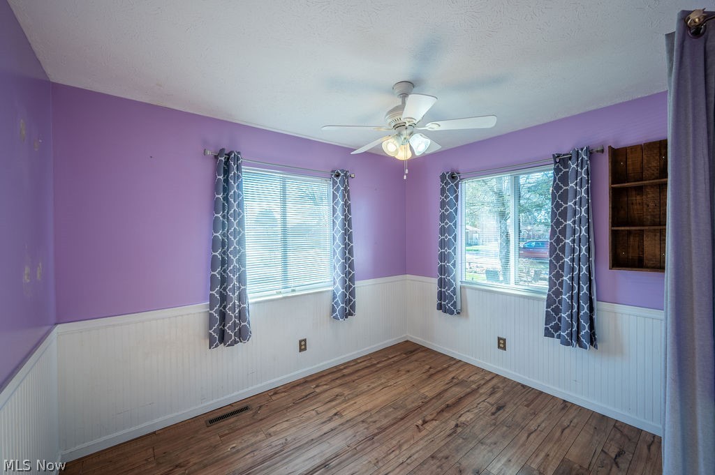3601 River Road Vienna, WV 26105 - Photo 22 of 40 Spare room featuring a ceiling fan, a wainscoted wall, hardwood / wood-style flooring, and healthy amount of natural light