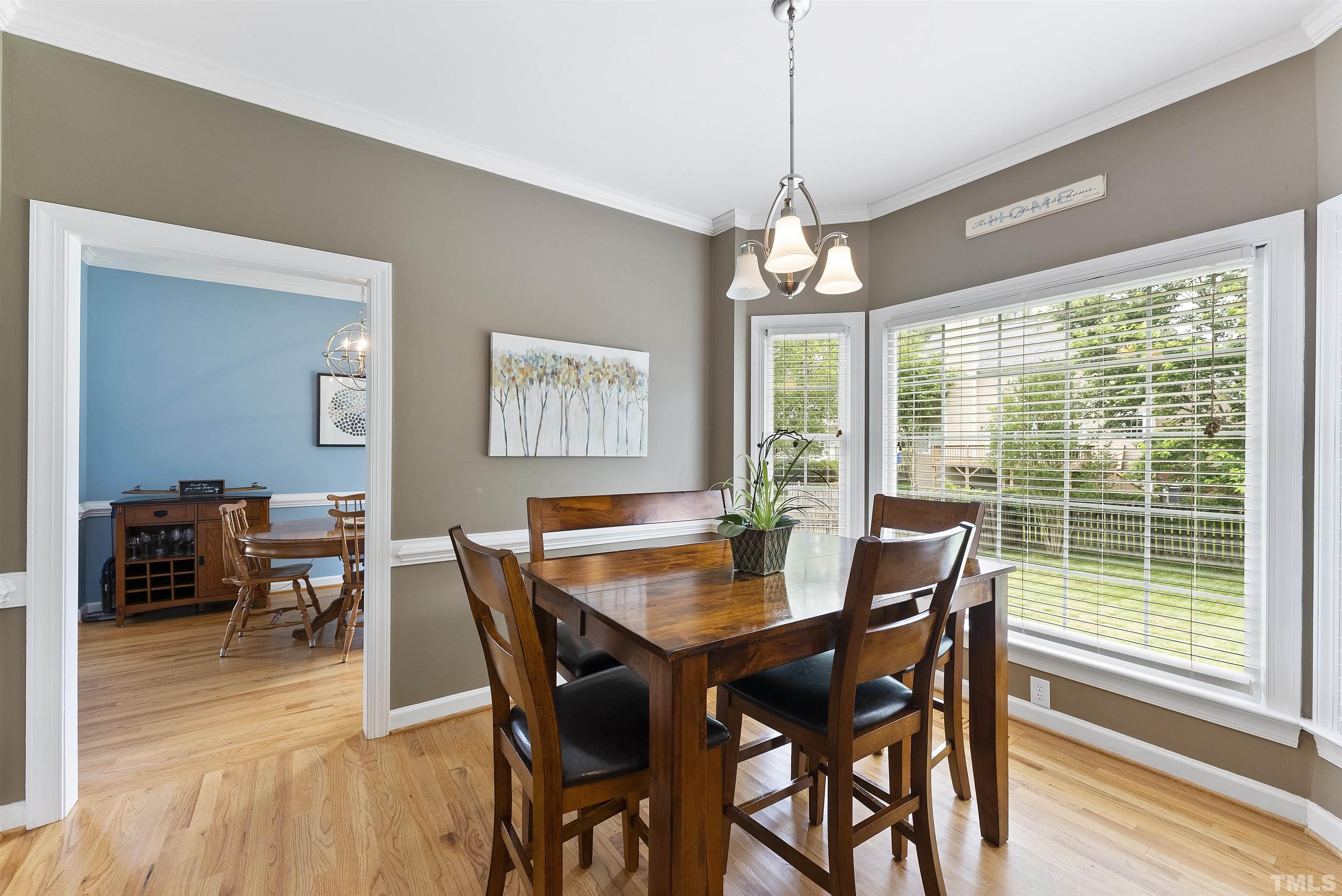 12304 Tappersfield Court Raleigh, NC 27613 - Photo 8 of 41 a dining room with wooden floor a chandelier a wooden table and chairs
