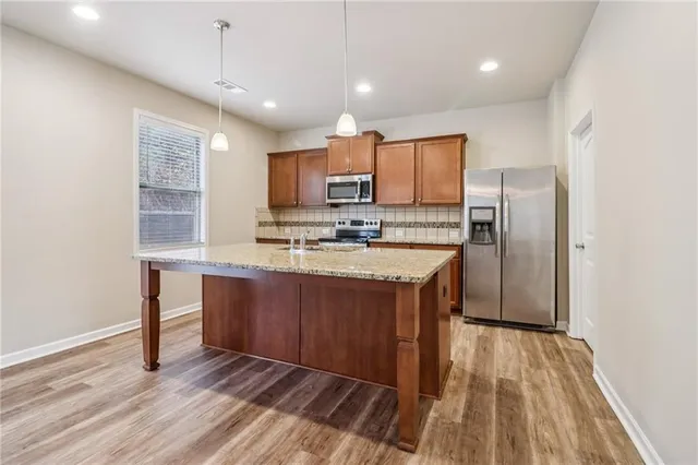 a kitchen with kitchen island granite countertop wooden floors white cabinets and stainless steel appliances