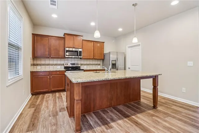 a kitchen with stainless steel appliances granite countertop a sink a stove and a wooden floors