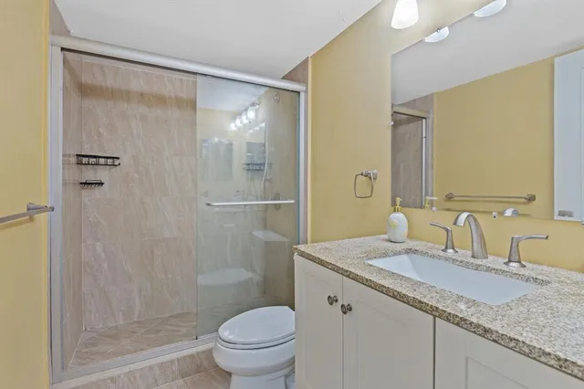 a bathroom with a granite countertop sink toilet and shower