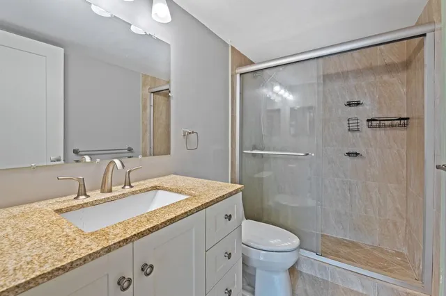 a bathroom with a granite countertop sink toilet and shower