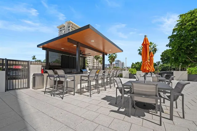 a view of a patio with dining table and chairs under an umbrella with palm trees
