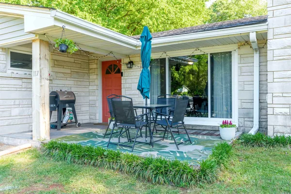 a view of a patio with table and chairs potted plants and a large tree