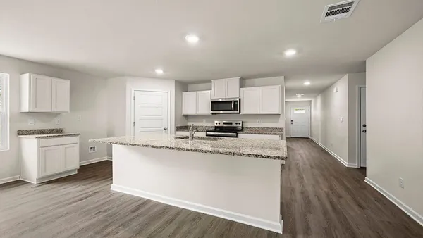 a large kitchen with granite countertop a stove top oven a sink a counter space and cabinets