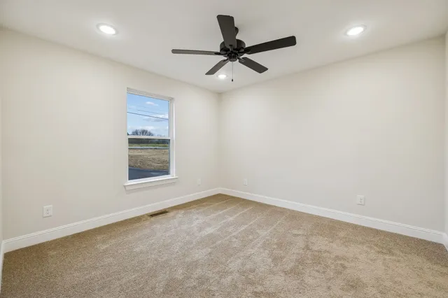 a view of a livingroom with a chandelier fan and windows