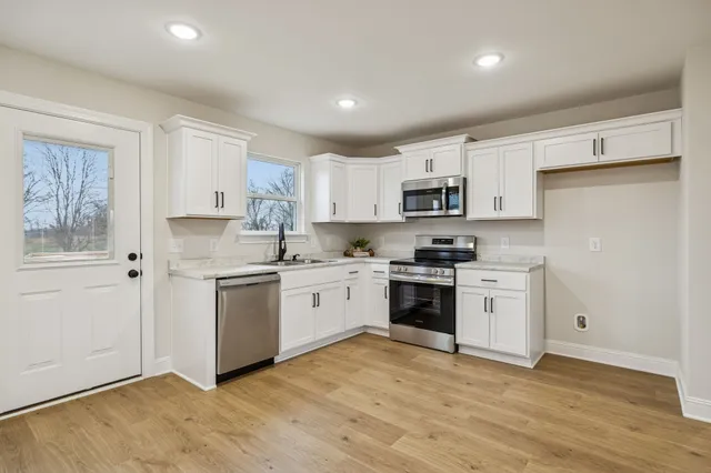 a kitchen with granite countertop white cabinets and stainless steel appliances