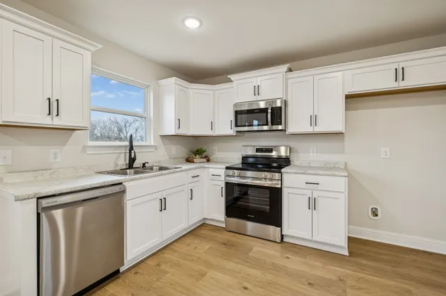 a kitchen with cabinets stainless steel appliances and a sink