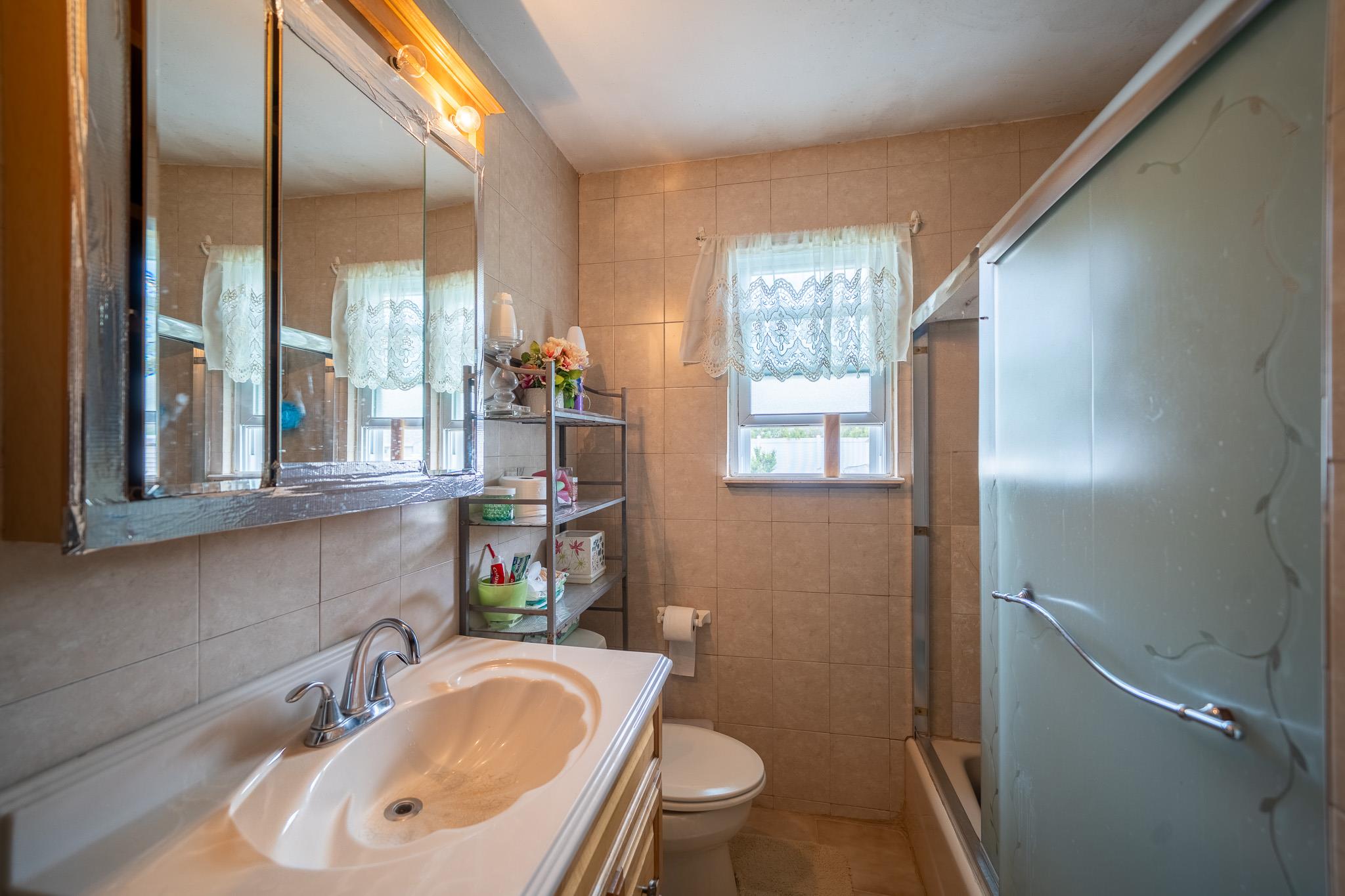47 Cardinal Road Levittown, NY 11756 - Photo 13 of 27 Bathroom featuring tile walls, vanity, shower / bath combination with glass door, and tile patterned flooring