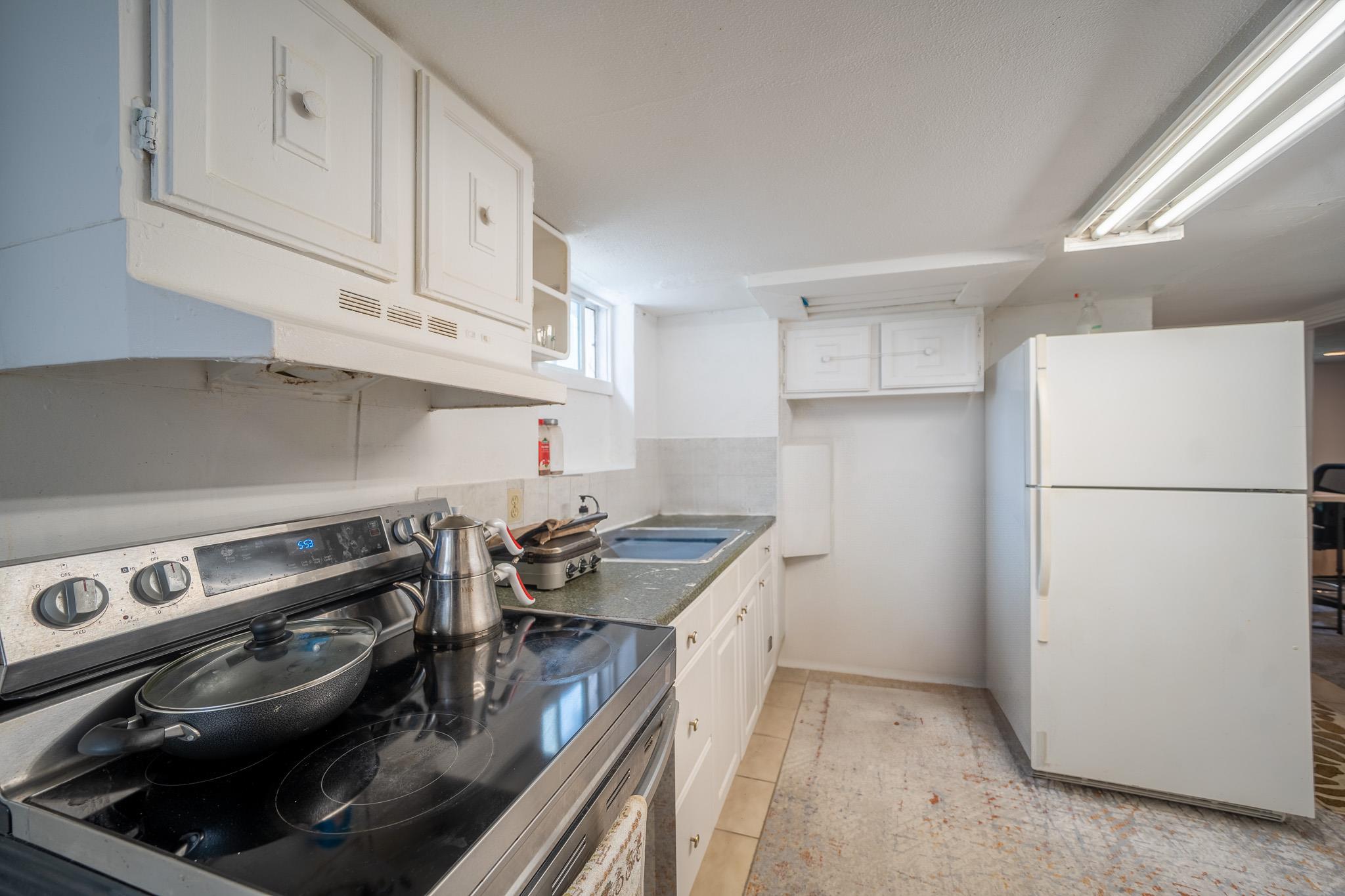 47 Cardinal Road Levittown, NY 11756 - Photo 19 of 27 Kitchen with freestanding refrigerator, stainless steel range with electric stovetop, white cabinets, under cabinet range hood, and open shelves