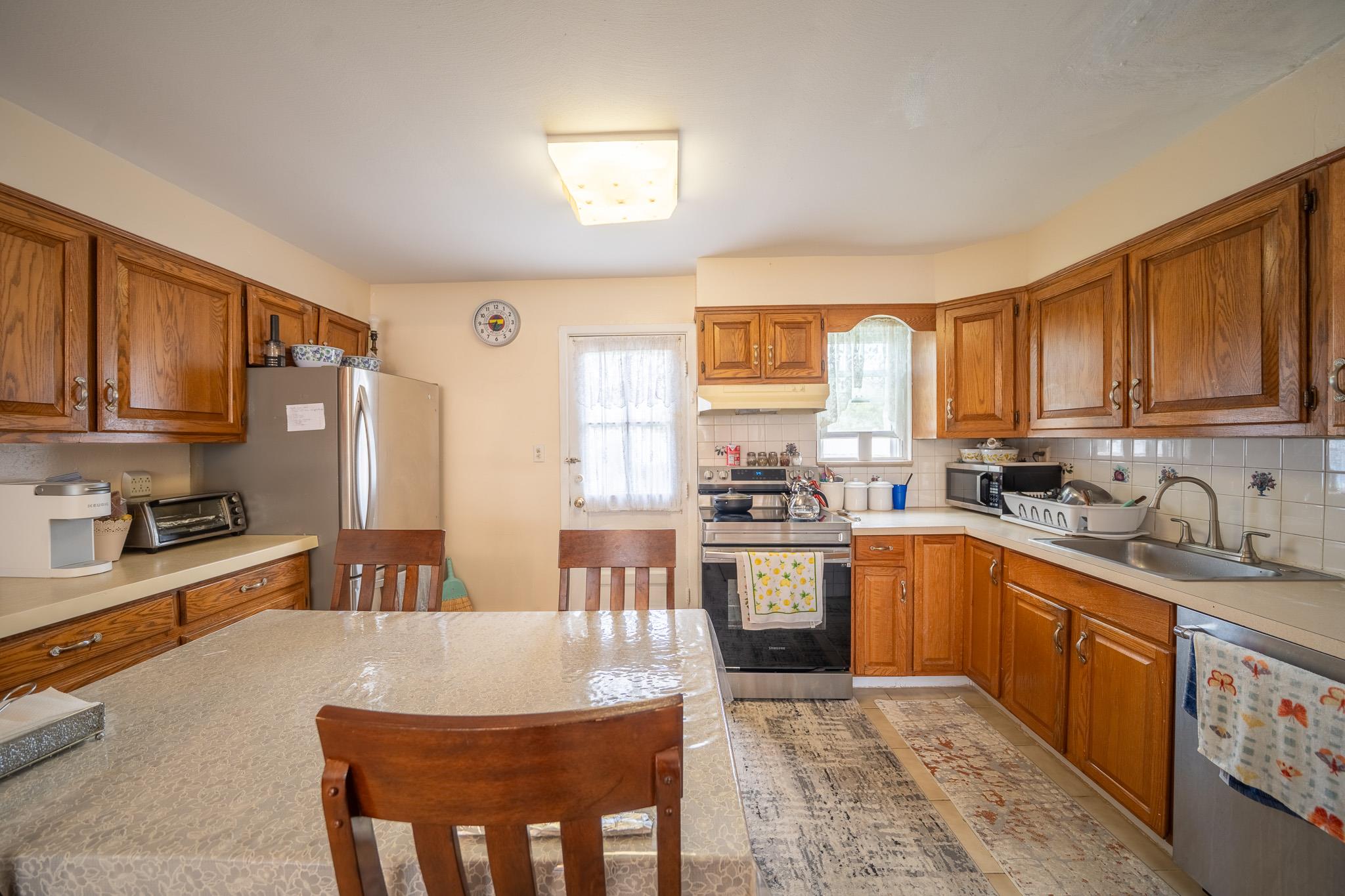 47 Cardinal Road Levittown, NY 11756 - Photo 6 of 27 Kitchen featuring appliances with stainless steel finishes, under cabinet range hood, light countertops, and brown cabinets