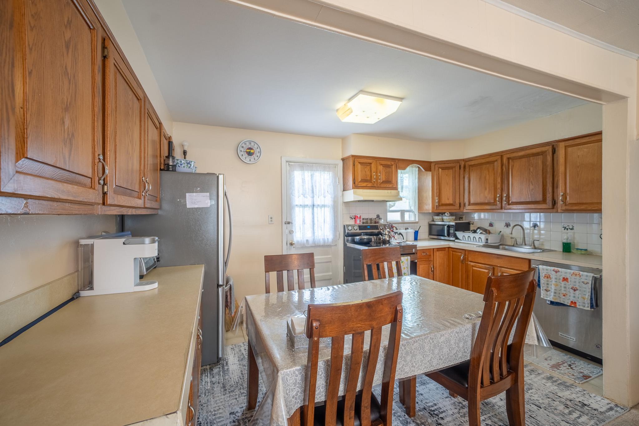 47 Cardinal Road Levittown, NY 11756 - Photo 7 of 27 Kitchen with appliances with stainless steel finishes, under cabinet range hood, decorative backsplash, light countertops, and brown cabinetry