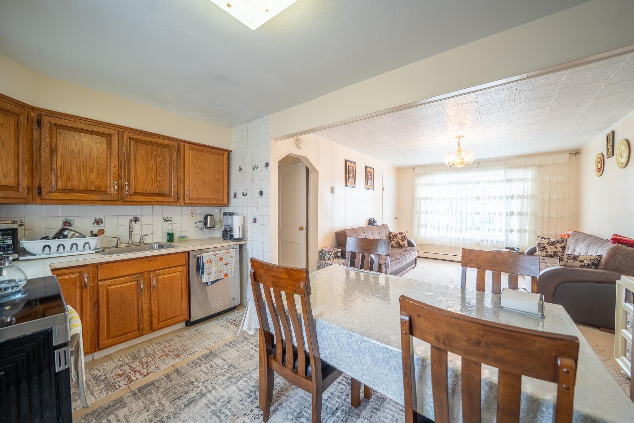 47 Cardinal Road Levittown, NY 11756 - Photo 8 of 27 Kitchen with stainless steel appliances, brown cabinets, light countertops, and a chandelier