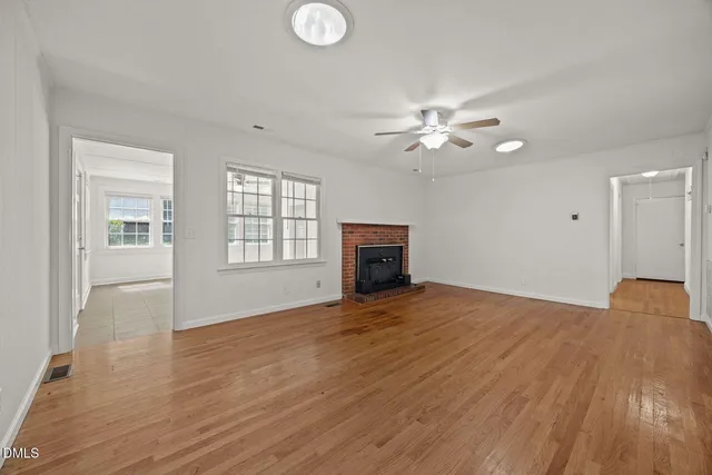 a view of an empty room with a window and wooden floor