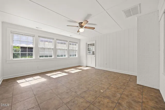 an empty room with windows and ceiling fan