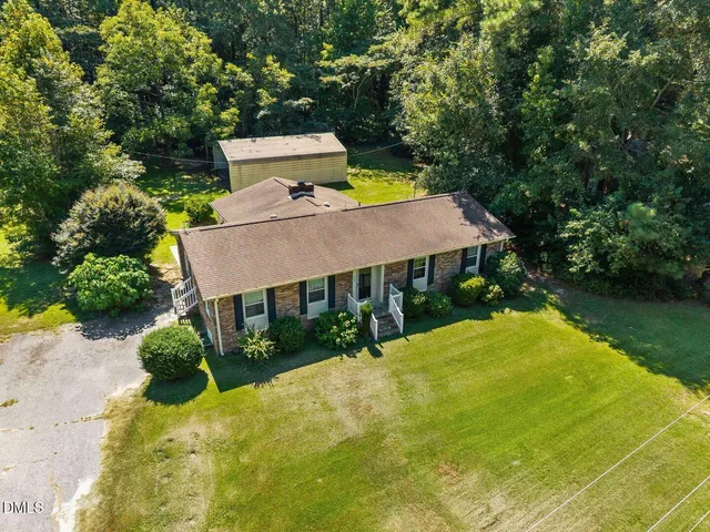 an aerial view of a house with swimming pool and yard with green space