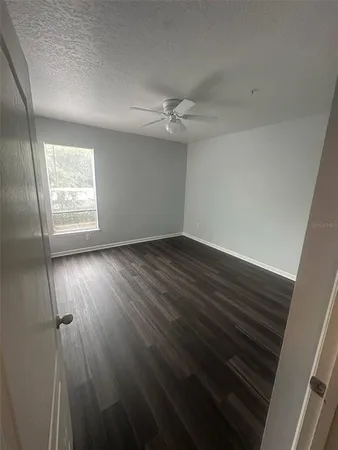 an empty room with wooden floor fan and windows