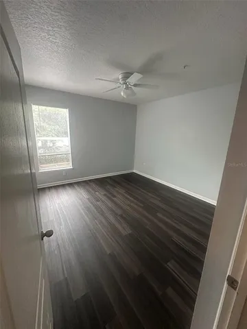 an empty room with wooden floor fan and windows