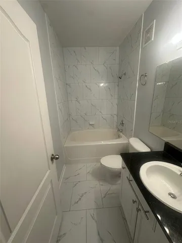 a bathroom with a granite countertop sink toilet a mirror and shower
