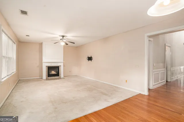 a view of an empty room with a window and kitchen view