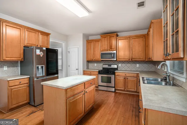 a kitchen with stainless steel appliances granite countertop a stove a sink dishwasher a refrigerator and dishwasher with wooden floor