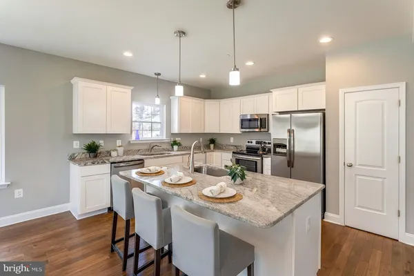 a kitchen with a refrigerator a stove a sink and a dining table with wooden floor