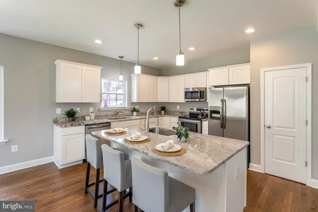 a kitchen with a refrigerator a stove a sink and a dining table with wooden floor