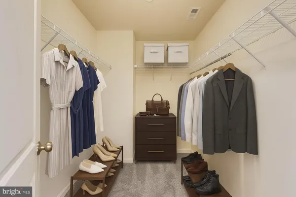 a view of walk in closet with clothes and shoes