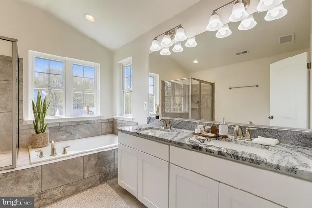 a bathroom with a granite countertop sink a large mirror and a bathtub with shower