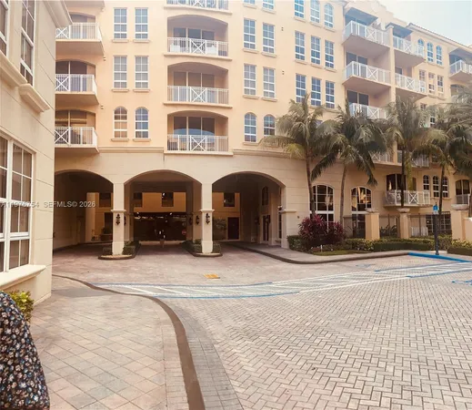 a view of a multi story residential apartment building with a yard and large trees