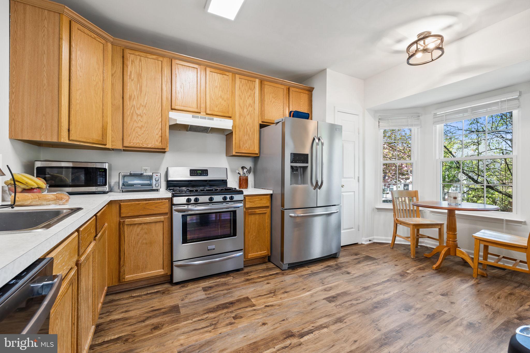8777 Dunstable Loop Bristow, VA 20136 - Photo 3 of 25 a kitchen with a refrigerator stove and wooden cabinets