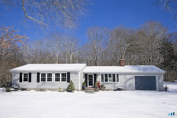 a front view of a house with a yard covered with snow