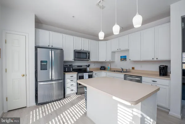 a kitchen with stainless steel appliances a refrigerator a stove a sink and white cabinets