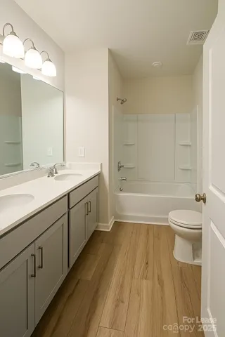 a spacious bathroom with a double vanity sink a toilet and a mirror