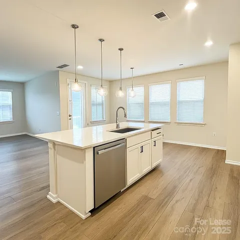 a large kitchen with stainless steel appliances granite countertop a sink a window and wooden floor