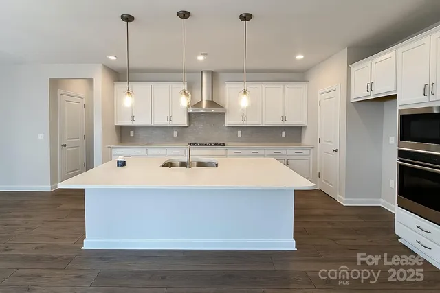 a view of kitchen with stainless steel appliances granite countertop a stove a sink a refrigerator and white cabinets