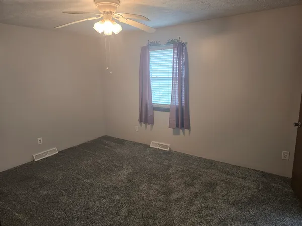 an empty room with windows and chandelier fan