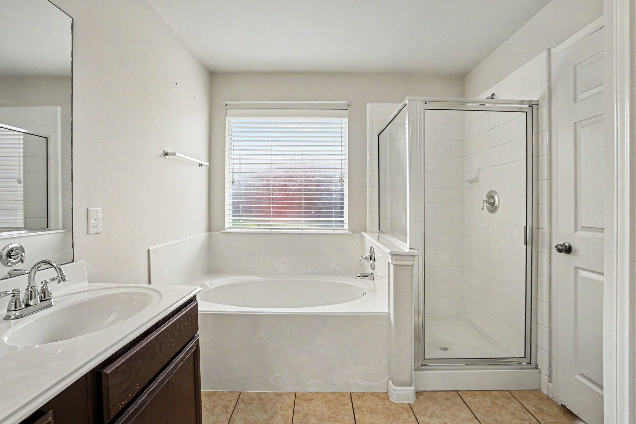 25222 Ginger Ranch Drive Katy, TX 77494 - Photo 23 of 33 Bright primary bathroom featuring a spacious soaking tub, separate glass-enclosed shower, and a sleek vanity with a large mirror. Neutral tile flooring and a window provide natural light.