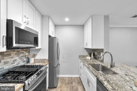 a kitchen with granite countertop a sink stainless steel appliances and cabinets