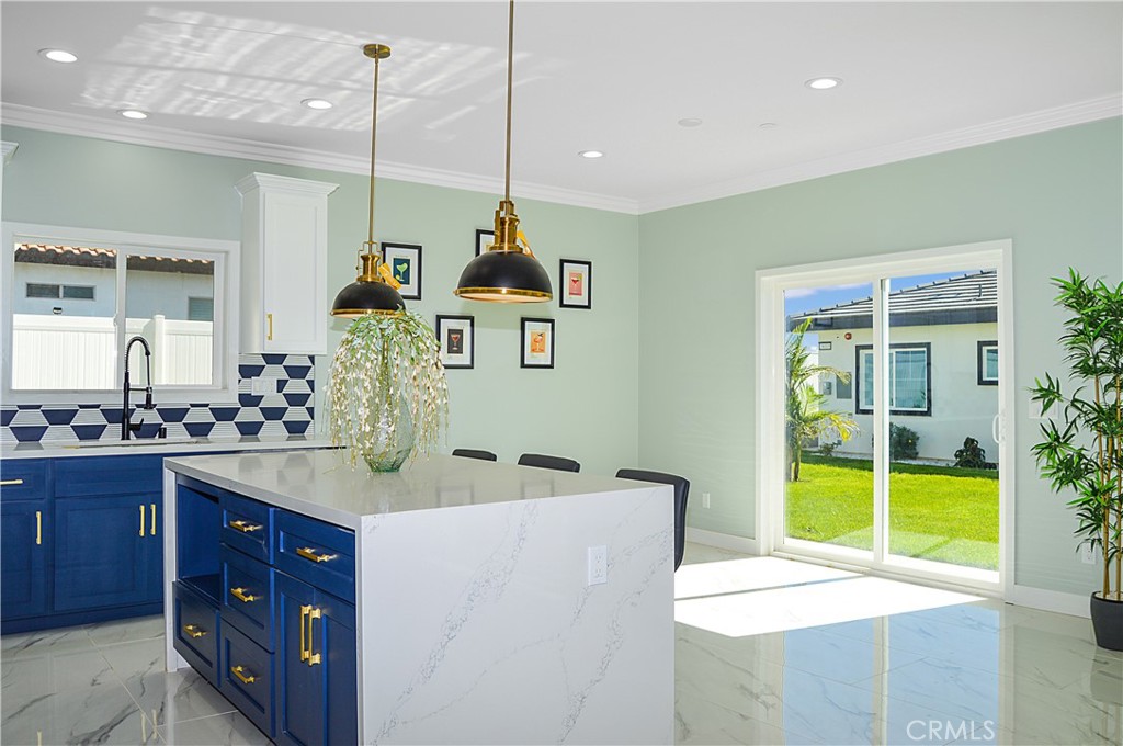 29329 Kemper Lane Highland, CA 92346 - Photo 20 of 75 Unit 1 - Designer-perfect kitchen with range, hood, dishwasher, tile backsplash, quartz counters, waterfall edge on island, and custom lighting