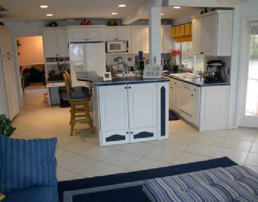 706 Irwin Lane Jupiter, FL 33458 - Photo 12 of 16 a kitchen with stainless steel appliances kitchen island granite countertop a stove a sink a refrigerator and white cabinets with wooden floor