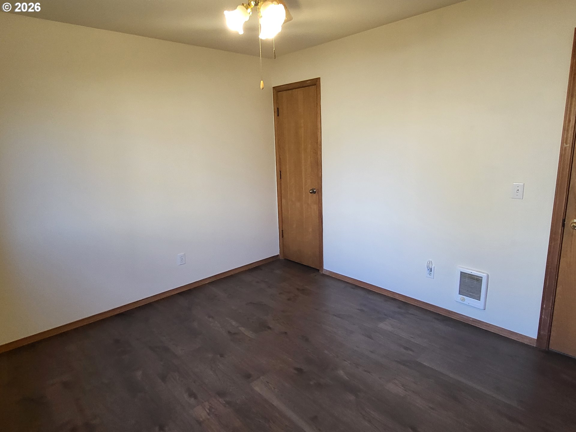 963 Crocker Street Coos Bay, OR 97420 - Photo 29 of 42 an empty room with a chandelier fan and wooden floor