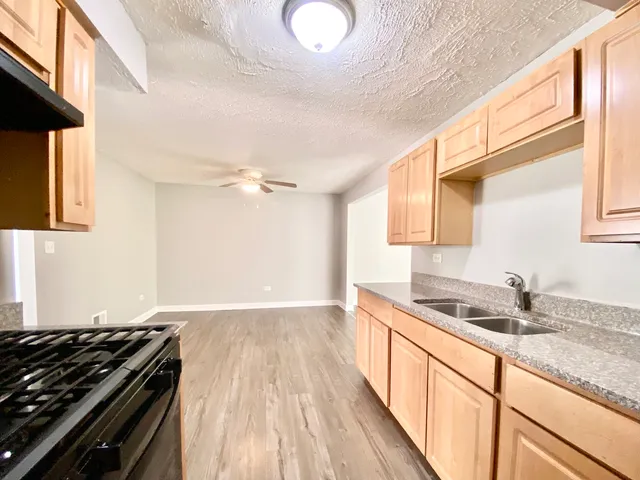 a kitchen with granite countertop a sink a stove cabinets and wooden floor
