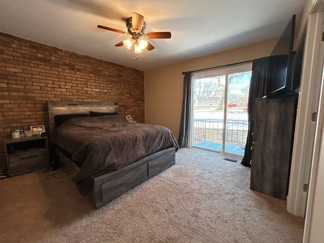 a bedroom with a bed next to a window with a balcony