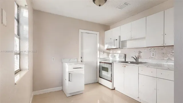 a kitchen with white cabinets sink and stove