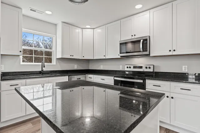 a kitchen with stainless steel appliances granite countertop a sink a microwave and wooden cabinets